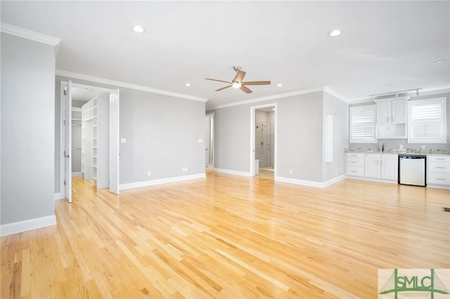 unfurnished living room featuring ceiling fan, light hardwood / wood-style floors, ornamental molding, and sink