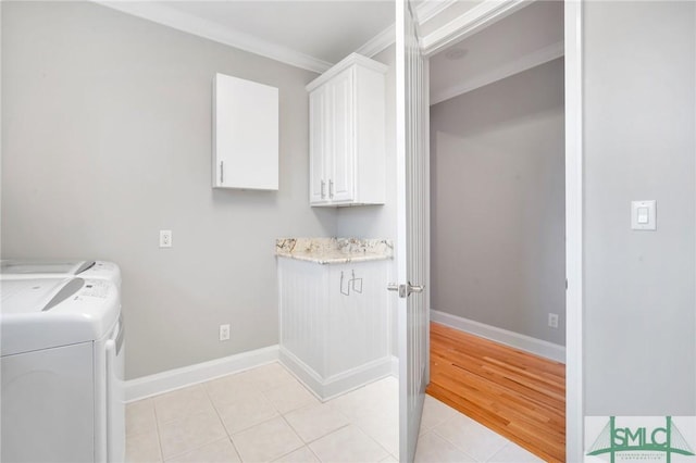 washroom featuring washer and dryer, light tile patterned floors, cabinets, and ornamental molding