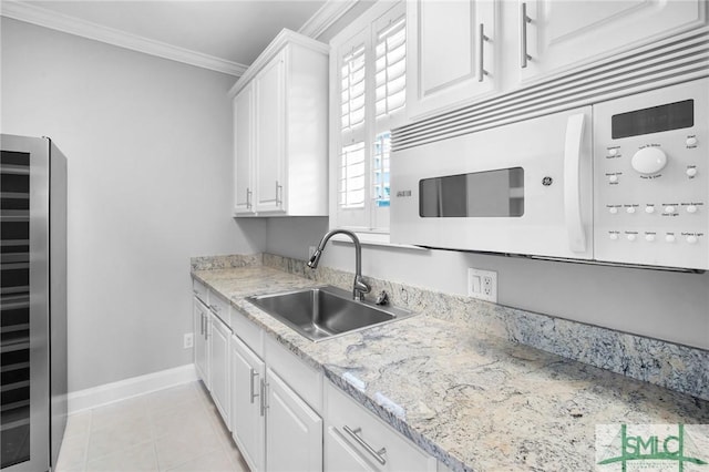 kitchen with sink, beverage cooler, white cabinets, crown molding, and light tile patterned flooring