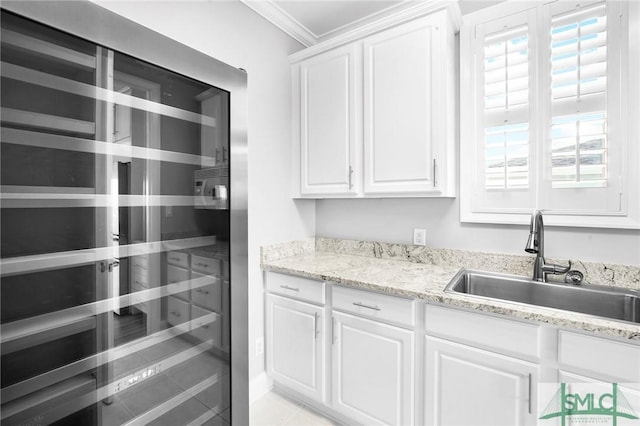 interior space featuring beverage cooler, crown molding, sink, white cabinetry, and plenty of natural light