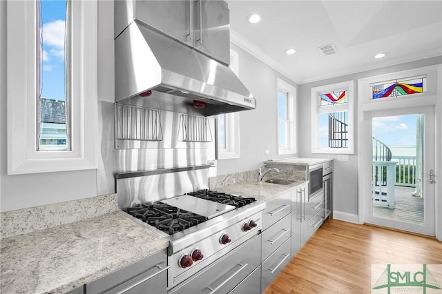 kitchen with gray cabinets, light stone countertops, ornamental molding, range hood, and stainless steel gas cooktop