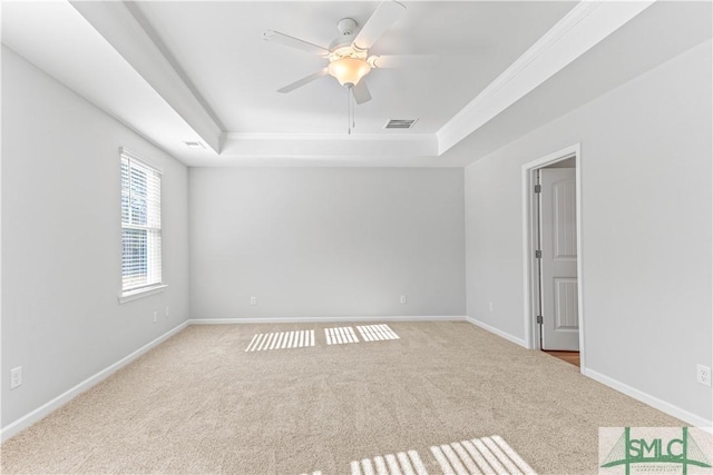 carpeted spare room with a raised ceiling and ceiling fan