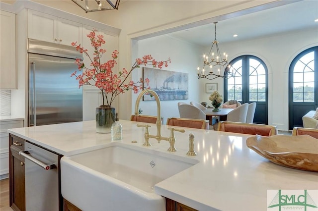 kitchen featuring sink, hanging light fixtures, stainless steel appliances, an inviting chandelier, and a breakfast bar