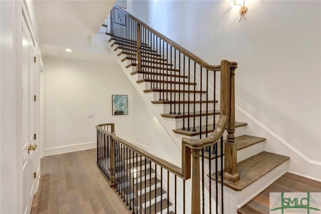 stairs with hardwood / wood-style flooring and ornamental molding