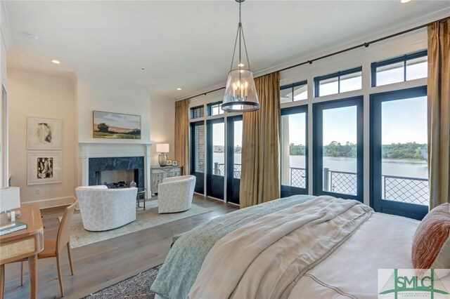 bedroom featuring a water view, wood-type flooring, a high end fireplace, and multiple windows