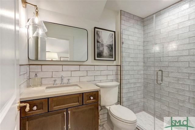 bathroom featuring walk in shower, vanity, toilet, and tile walls