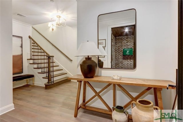 interior space with a chandelier, crown molding, and wood-type flooring