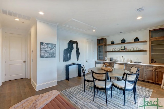 dining room featuring crown molding, light hardwood / wood-style flooring, and wet bar