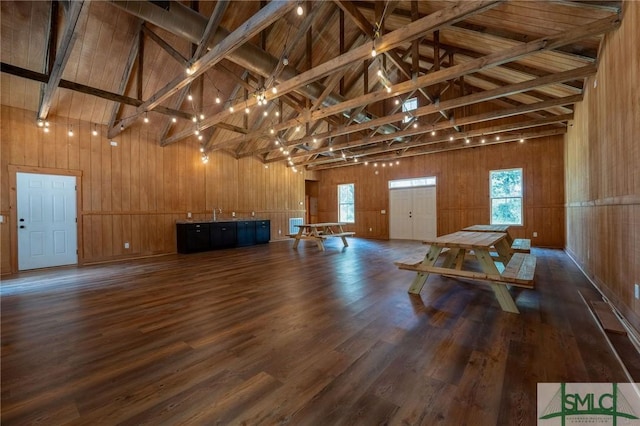 miscellaneous room featuring wooden walls, beam ceiling, dark wood-type flooring, and high vaulted ceiling