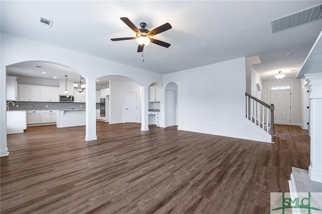 12 Cottonfield Dr, Guyton, GA 31312 - unfurnished living room with ceiling fan, dark wood-style flooring, stairs, and arched walkways