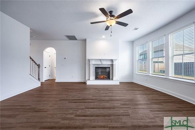 unfurnished living room featuring ceiling fan, dark hardwood / wood-style flooring, and a textured ceiling