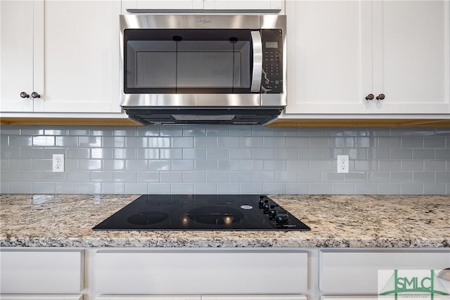 kitchen with white cabinetry, black electric cooktop, and tasteful backsplash