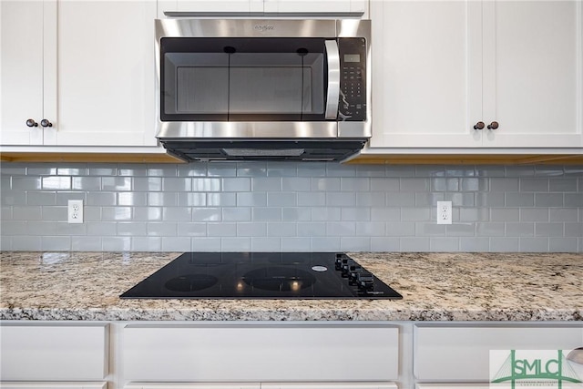 12 Cottonfield Dr, Guyton, GA 31312 - kitchen featuring stainless steel microwave, black electric stovetop, white cabinetry, and tasteful backsplash