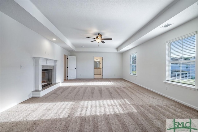 unfurnished living room with light colored carpet, ceiling fan, and a tray ceiling