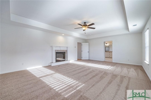 unfurnished living room featuring light colored carpet, a raised ceiling, and ceiling fan