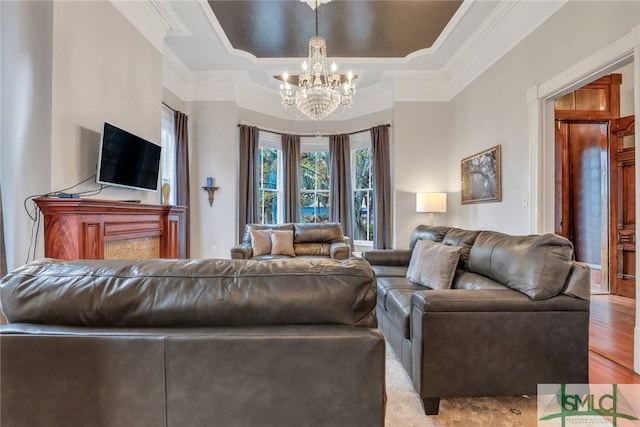 living room with light hardwood / wood-style flooring, crown molding, a tray ceiling, and a chandelier