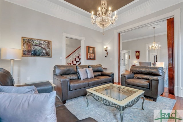 living room with a raised ceiling, an inviting chandelier, wood-type flooring, and ornamental molding