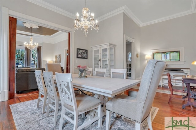 dining area featuring hardwood / wood-style flooring, crown molding, and an inviting chandelier