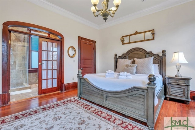 bedroom featuring hardwood / wood-style floors, ensuite bathroom, crown molding, and a chandelier