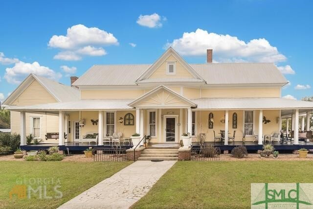 farmhouse inspired home featuring a front lawn and covered porch