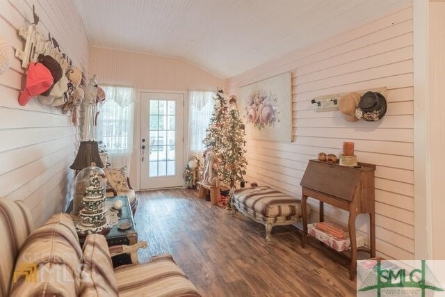 sitting room with lofted ceiling, wooden walls, and hardwood / wood-style floors