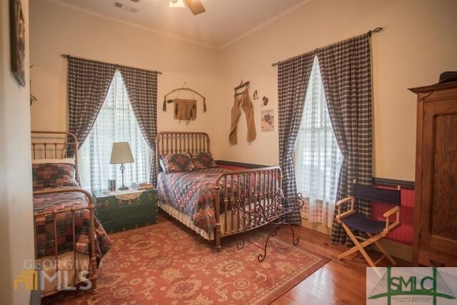 bedroom with hardwood / wood-style floors, ornamental molding, and ceiling fan