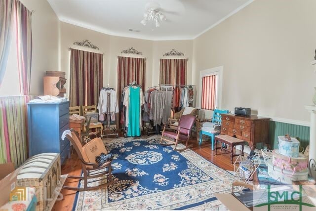 living area featuring ornamental molding, wood-type flooring, and ceiling fan