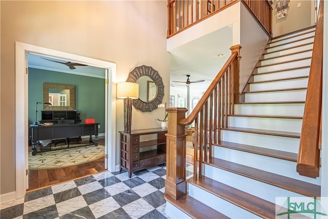 stairway featuring ceiling fan, a towering ceiling, ornamental molding, and hardwood / wood-style flooring