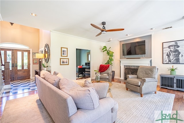 living room featuring a tile fireplace, ceiling fan, hardwood / wood-style floors, and ornamental molding