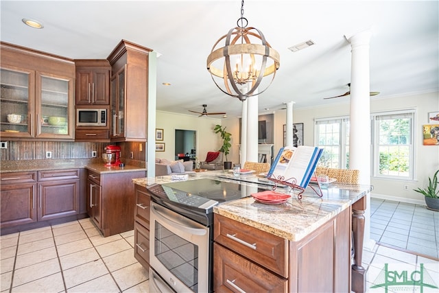 kitchen featuring pendant lighting, white microwave, electric stove, light stone countertops, and decorative columns