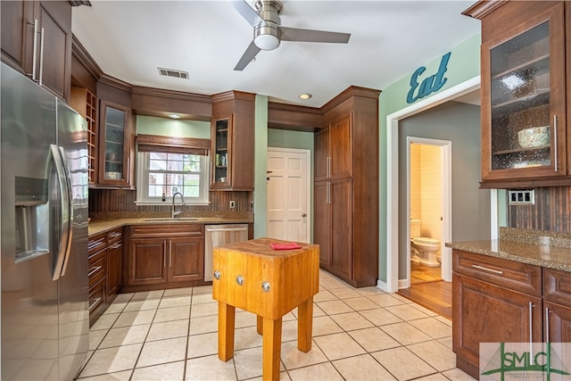 kitchen featuring light stone counters, sink, light tile patterned floors, and stainless steel appliances