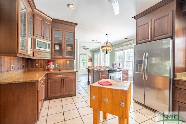 kitchen featuring a center island, ceiling fan with notable chandelier, hanging light fixtures, appliances with stainless steel finishes, and tasteful backsplash