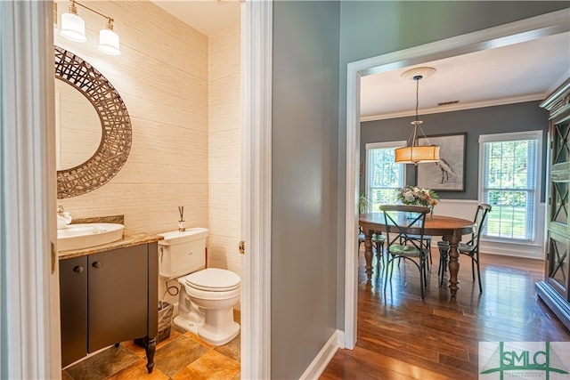 bathroom featuring ornamental molding, vanity, wood-type flooring, toilet, and wood walls