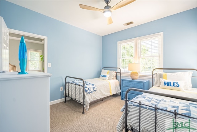 carpeted bedroom featuring multiple windows and ceiling fan