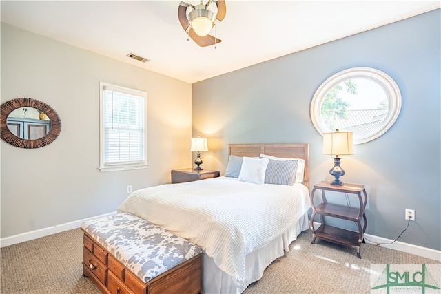 carpeted bedroom with ceiling fan and multiple windows