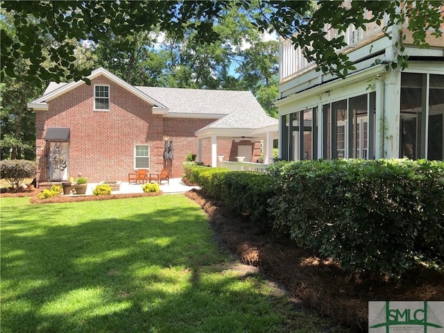 exterior space featuring a sunroom, a patio area, and a front lawn