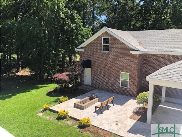 rear view of property with a lawn, a patio area, and an outdoor fire pit