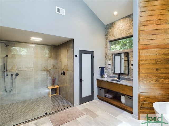 bathroom with vanity, high vaulted ceiling, and a tile shower