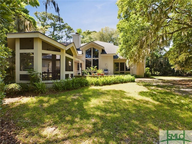 rear view of house with a sunroom and a yard