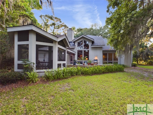 rear view of property featuring a lawn and a sunroom