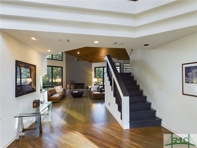 staircase featuring hardwood / wood-style flooring, wooden ceiling, ceiling fan, and a towering ceiling