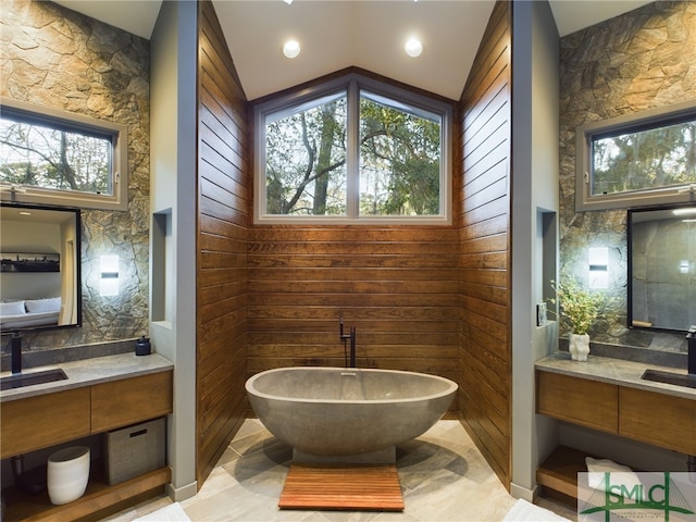 bathroom with tasteful backsplash, vanity, a bathing tub, and vaulted ceiling