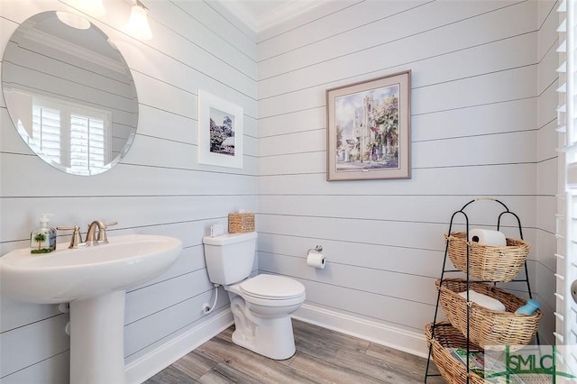 bathroom featuring hardwood / wood-style flooring, toilet, ornamental molding, and wooden walls