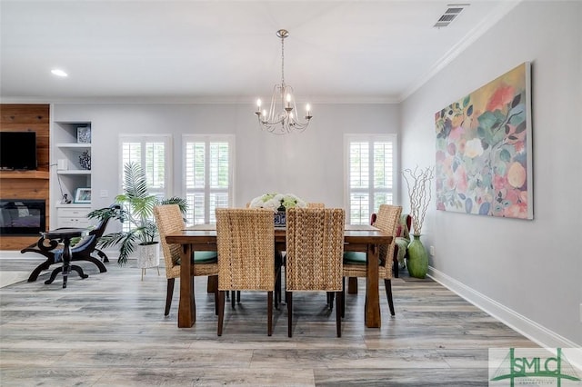 dining room with light hardwood / wood-style flooring, crown molding, and a notable chandelier