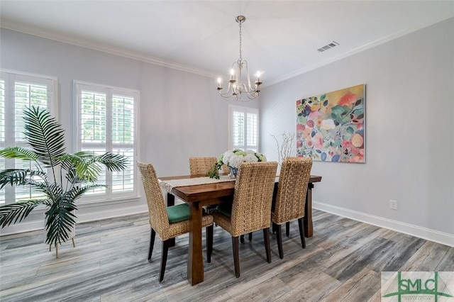 dining room featuring hardwood / wood-style floors, ornamental molding, and a chandelier