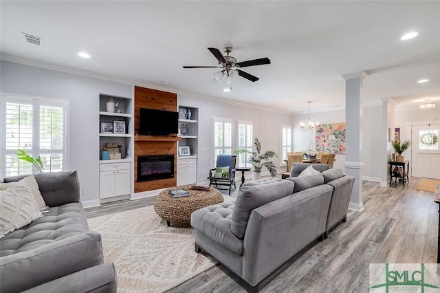 living room with built in features, crown molding, a wealth of natural light, and light hardwood / wood-style flooring