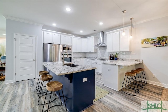 kitchen featuring white cabinets, a breakfast bar, wall chimney range hood, and hanging light fixtures