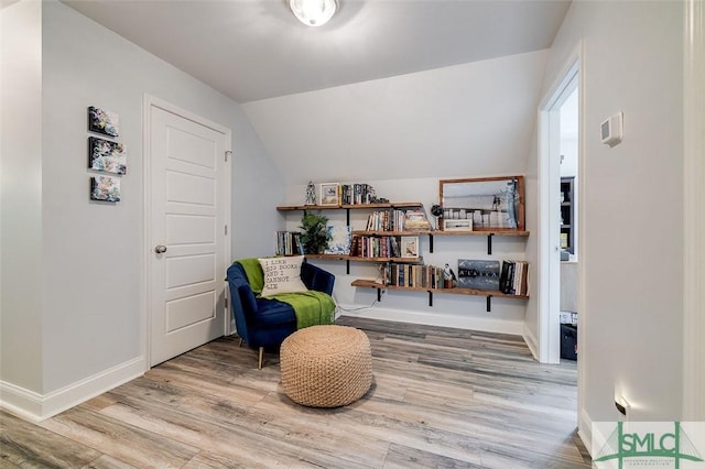 sitting room with hardwood / wood-style floors and vaulted ceiling