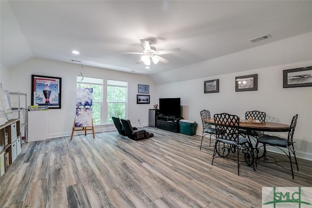 living room with ceiling fan, light hardwood / wood-style floors, and vaulted ceiling