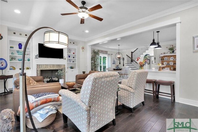 living room with a fireplace, dark hardwood / wood-style flooring, ceiling fan, and ornamental molding